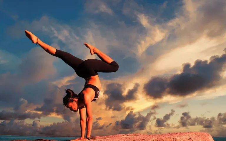 Woman gymnast outdoors on rock ledge practicing her craft.