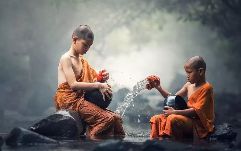 Two young Buddhist monks washing bowls in the river.
